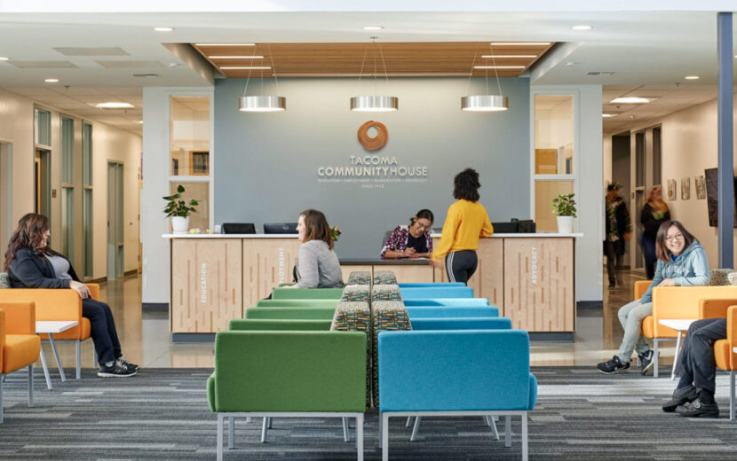 The main lobby of the Tacoma Community House building with colorful chairs and people sitting, standing, or talking.